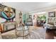 Bright living room with stylish seating, decorative rug, art, and a view into the dining area at 5027 Castlewood Sw Dr, Lilburn, GA 30047
