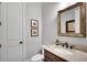 Compact half bathroom with a marble countertop, framed mirror, and white fixtures at 10140 Grandview Sq, Duluth, GA 30097