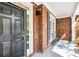 Inviting covered front porch features a brick facade and a black front door with sidelight and a place to sit at 8640 Amsbury Way, Cumming, GA 30041