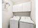 A well-lit laundry room featuring a full sized washer and dryer, with white cabinets at 8640 Amsbury Way, Cumming, GA 30041
