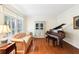 Charming living room features a piano, hardwood floors, large windows with shutters, and neutral paint at 8640 Amsbury Way, Cumming, GA 30041