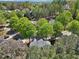 Aerial shot of the surrounding neighborhood, showcasing lush trees and nearby houses in a residential area at 8640 Amsbury Way, Cumming, GA 30041