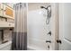 White tiled shower and tub combination featuring a rainfall shower head and gray and white color-blocked shower curtain at 2166 Sonoma Se Dr, Smyrna, GA 30080