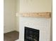 Close-up of a cozy fireplace with white brick surround and wooden mantle at 6490 Mockingbird Rd, Cumming, GA 30028