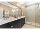Bathroom with double sinks, dark cabinets, large mirror, and a glass-enclosed shower at 130 Inwood Walk, Woodstock, GA 30188