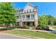 Elegant townhome showcasing a covered balcony, brick accents, and lush landscaping for curb appeal at 130 Inwood Walk, Woodstock, GA 30188