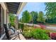 Charming front porch view with rocking chairs, surrounded by a beautifully landscaped garden and brick details at 130 Inwood Walk, Woodstock, GA 30188