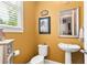 Cozy powder room with mustard color walls, pedestal sink and toilet; a convenient space for guests at 130 Inwood Walk, Woodstock, GA 30188