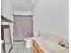 Tiled bathroom features a toilet, sink, shower with patterned curtain and mirror at 7737 Bar Harbor Dr, Riverdale, GA 30296