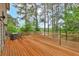 Spacious wooden deck with an outdoor dining set and lake views through the trees at 7737 Bar Harbor Dr, Riverdale, GA 30296