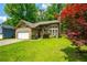 Charming single-Gathering home with a stone and siding exterior, well-manicured lawn, and a red maple tree at 1131 Bailing Dr, Lawrenceville, GA 30043