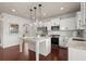 Open concept kitchen features white cabinets, stainless appliances, a stylish tile backsplash, and a granite island at 5760 Palmtree Pass, Cumming, GA 30040
