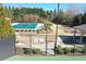 Aerial view of a fenced community pool, playground and tennis courts surrounded by trees and landscaping at 5760 Palmtree Pass, Cumming, GA 30040