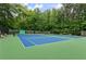 Community tennis courts with a net and greenery surrounding at 1440 Sandford Sw Trl, Lilburn, GA 30047