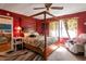 Primary bedroom with red walls, decorative canopy bed, ceiling fan and an ornate window at 2004 Poplar Falls Rd, Lithonia, GA 30058