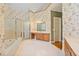 Large bathroom featuring a jacuzzi tub, tiled floor and shower with gold trim and vanity area at 7830 Kings Point Dr, Cumming, GA 30041