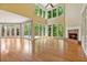 Spacious living room with hardwood floors, fireplace, and a wall of windows showcasing the outdoor view at 7830 Kings Point Dr, Cumming, GA 30041
