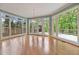 Sun-drenched living room with hardwood floors and walls of windows overlooking the lush greenery at 7830 Kings Point Dr, Cumming, GA 30041