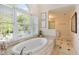 Bright bathroom featuring a soaking tub beneath a large window with natural light at 3003 W Roxboro Rd, Atlanta, GA 30324