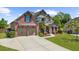 Stately brick home featuring a manicured lawn, mature trees, a three-car garage, and a covered front entrance at 5950 Hidden Ridge Ct, Cumming, GA 30028