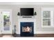 A cozy fireplace with a black surround, a white mantle, a television above and an exterior view at 5950 Hidden Ridge Ct, Cumming, GA 30028