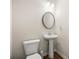 Compact powder room with a pedestal sink, round mirror, and modern lighting fixtures at 6372 Rosetta Sw Dr, Atlanta, GA 30331