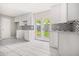 Well-lit kitchen featuring white cabinets and mosaic backsplash, with backyard access at 2529 Ryne St, Atlanta, GA 30318