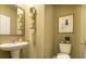 Well-lit bathroom with pedestal sink, toilet, decorative wall art, and decorative live plants at 4960 Jatoba Rd, Acworth, GA 30101