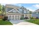 Two-story home features gray siding, stone accents, manicured lawn and large, concrete driveway at 2625 Blackstock Dr, Cumming, GA 30041