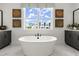 Bright bathroom features a modern soaking tub, marble floors, and large window views at 326 Treble Way, Alpharetta, GA 30009