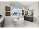 Bright bathroom features a modern soaking tub, marble floors, and large window views at 326 Treble Way, Alpharetta, GA 30009