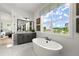Bright bathroom features a modern soaking tub, marble floors, and large window views at 326 Treble Way, Alpharetta, GA 30009