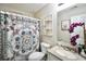 Well-lit bathroom features a patterned shower curtain, toilet, vanity with decorative plants and mirror at 701 Monticello Ln, Mcdonough, GA 30253