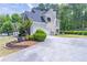 A long driveway leads to a tan home with a 2 car garage and manicured landscaping on a sunny day at 4319 Silver Peak Pkwy, Suwanee, GA 30024