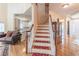 Bright foyer featuring hardwood floors, staircase with red runners, and views into the living room and front door at 4319 Silver Peak Pkwy, Suwanee, GA 30024