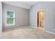 A carpeted bedroom with gray walls featuring a window and doorway leading to a connected bathroom at 4360 Havenridge Pl, Cumming, GA 30041