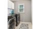 A practical laundry room with modern washer and dryer, overhead cabinets, and a patterned rug at 4360 Havenridge Pl, Cumming, GA 30041