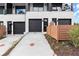 Modern townhome with black garage doors, light brick facade, and a fenced-in front yard at 654 Soul Aly # 102, Alpharetta, GA 30009