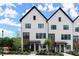 Modern townhome exterior featuring black-framed windows, a painted brick facade, and well manicured landscaping at 654 Soul Aly # 102, Alpharetta, GA 30009