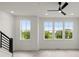 Living room featuring many windows, a modern ceiling fan, and staircase with black metal railing at 673 Soul Aly # 146, Alpharetta, GA 30009