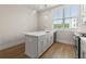 A kitchen island has a white countertop, sink, and cabinets providing ample space, complemented by pendant lighting at 656 Soul Aly # 101, Alpharetta, GA 30009