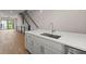 A kitchen island features a stainless steel sink and white countertop leading to an open-concept living area at 656 Soul Aly # 101, Alpharetta, GA 30009