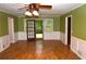 Inviting living room featuring hardwood floors, wainscoting and a ceiling fan with backyard access at 553 Old Mill Ct, Norcross, GA 30093