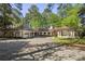 Mediterranean-style home with brick driveway, multiple garages, and covered porch, framed by mature trees at 9355 Huntcliff Trce, Sandy Springs, GA 30350