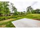 Backyard with a grass hill and concrete patio space surrounded by mature trees at 1800 Forkview Ct, Lawrenceville, GA 30044