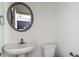 Stylish half bathroom with a circular mirror, pedestal sink, and modern toilet at 1800 Forkview Ct, Lawrenceville, GA 30044