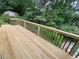 View of a backyard deck surrounded by trees with partial views of an in-ground pool and storage shed at 225 Nacoochee Dr, Woodstock, GA 30188
