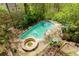 Aerial view of a kidney-shaped pool surrounded by trees with a hot tub nearby at 225 Nacoochee Dr, Woodstock, GA 30188