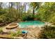 Backyard aerial view of a sparkling swimming pool and hot tub surrounded by lush trees at 225 Nacoochee Dr, Woodstock, GA 30188