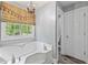 Bright bathroom featuring a soaking tub with jets, a large window, and wood-look flooring at 24 Picketts Mill Pl, Acworth, GA 30101